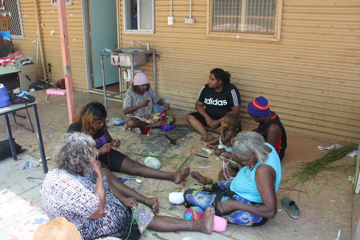 Lily Long (centre pink beanie) teaching the ladies to weave